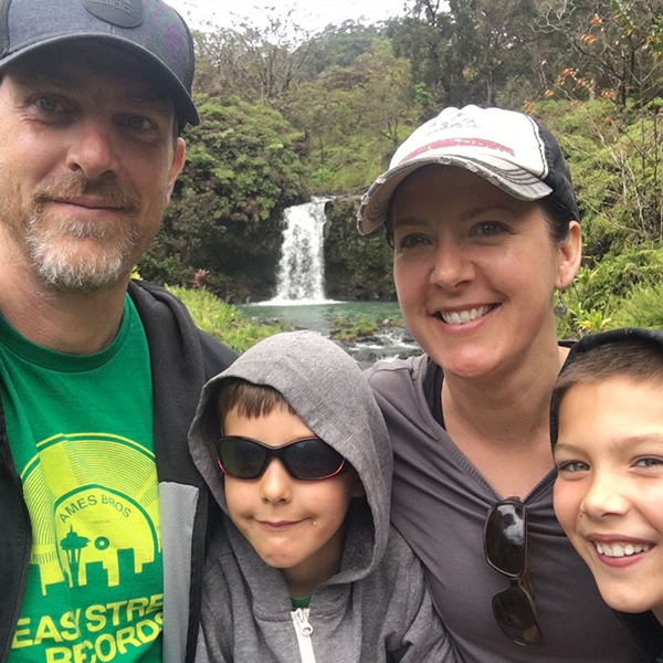 Family of four smiles at camera with waterfall behind them
